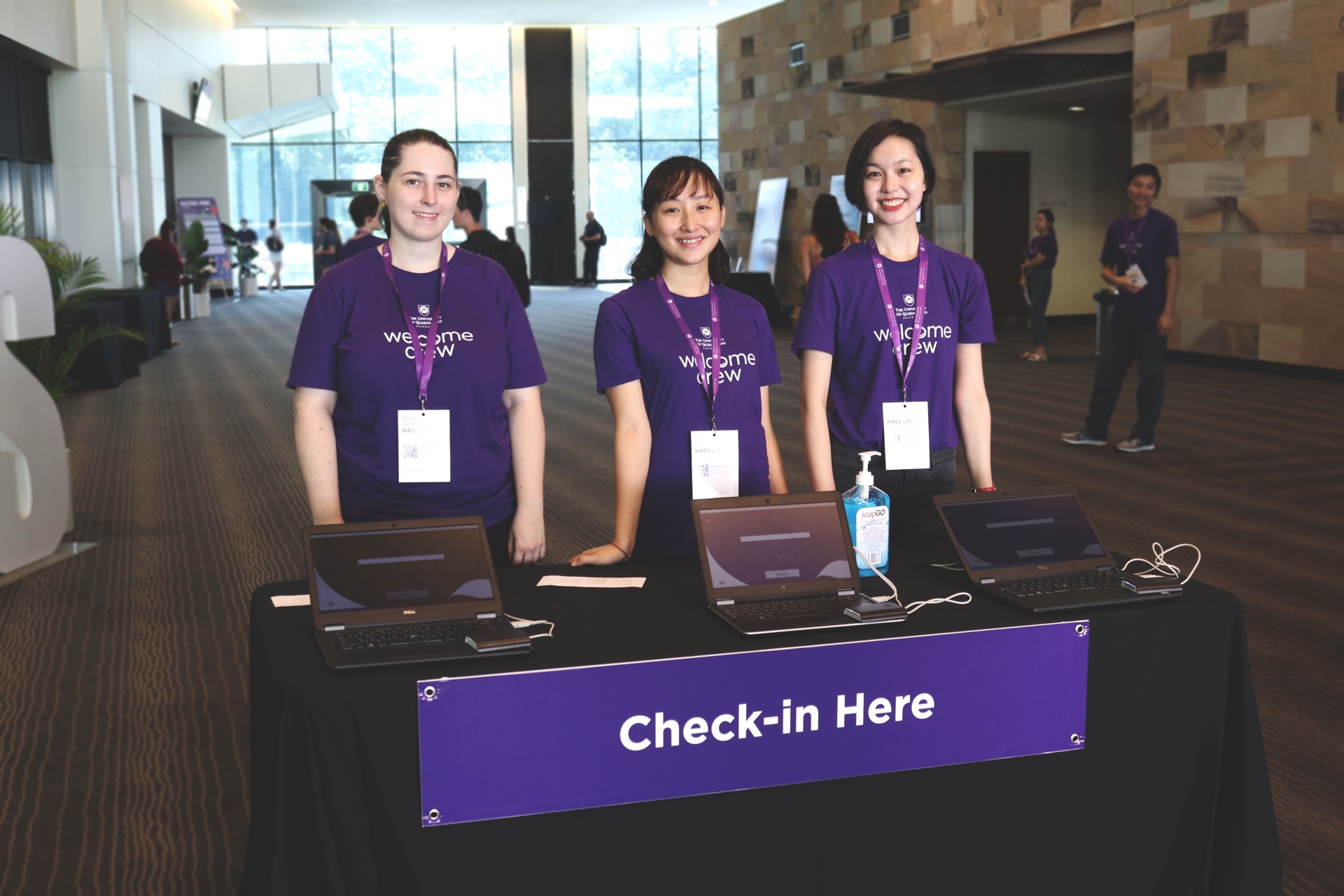 Three HASS volunteers standing at a check in desk of an orientation event.