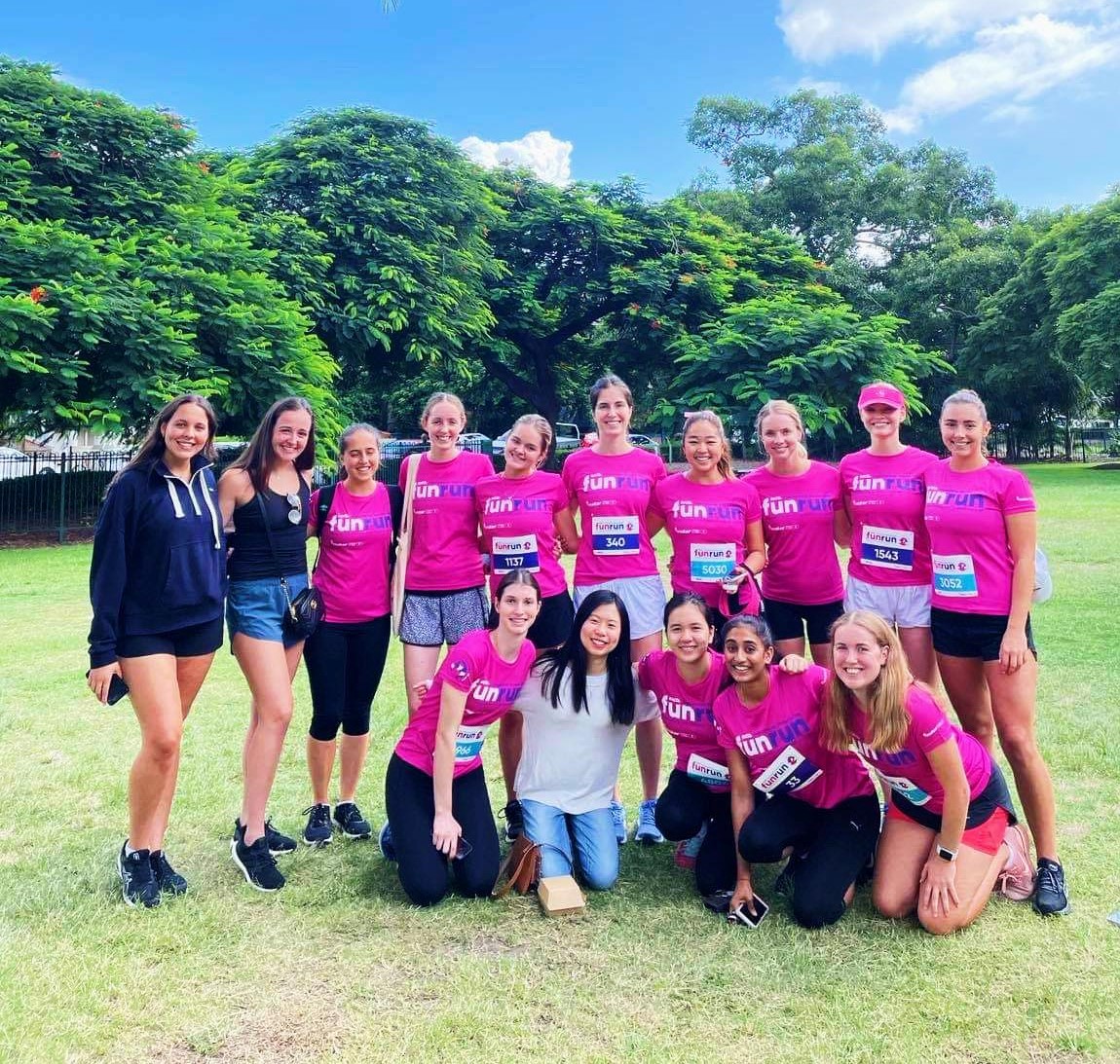 15 women pose in pink shirts after compling the International Women's Day Fun Run supporting breast cancer research