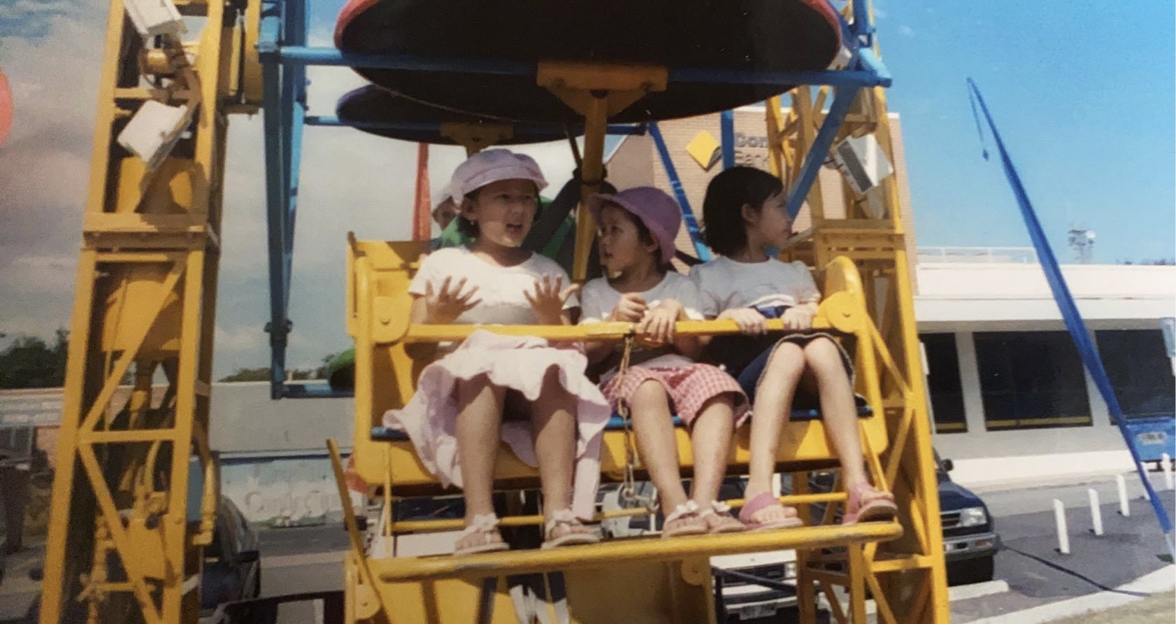 Three young asian girls sitting on a ferris wheel attraction. 