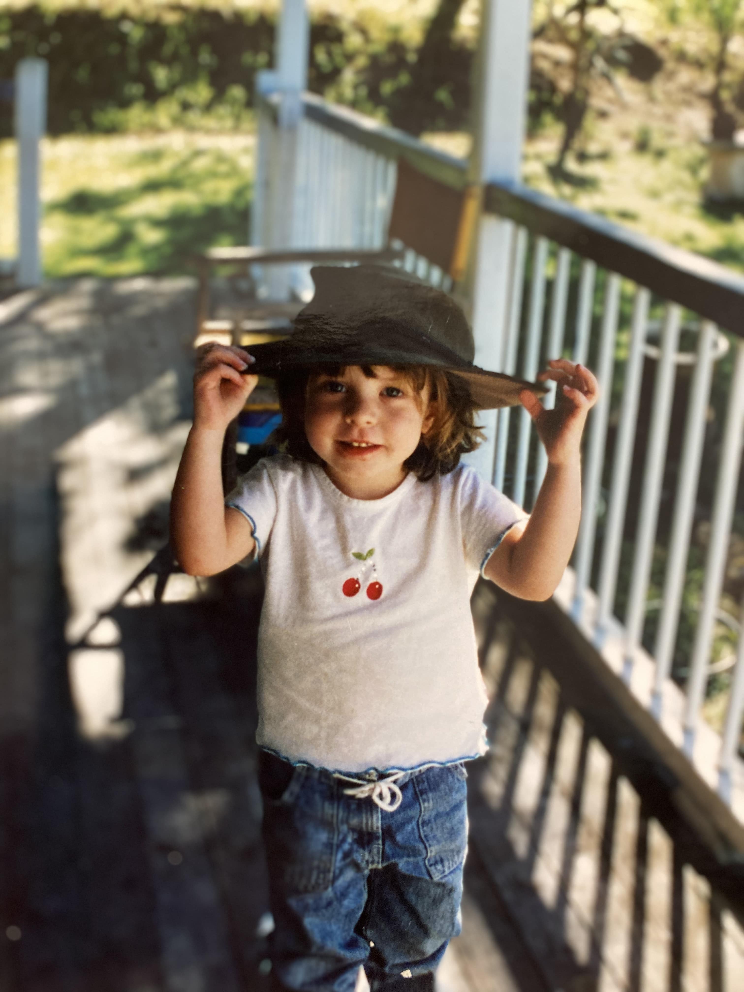 small child with wide brimmed hat looking at camera