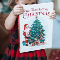 Girl holding 'The Night Before Christmas' book.